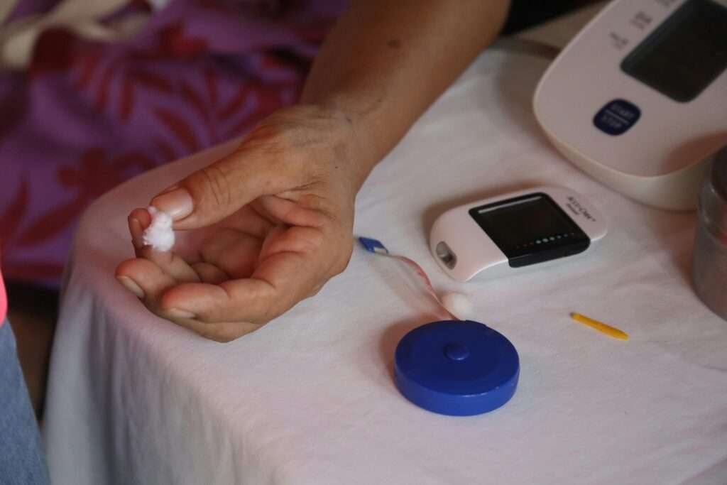 Persona adulta realizándose una prueba de glucosa en el dedo con un glucómetro, en un entorno hogareño, simbolizando el autocuidado y monitoreo diario en la diabetes tipo 2.