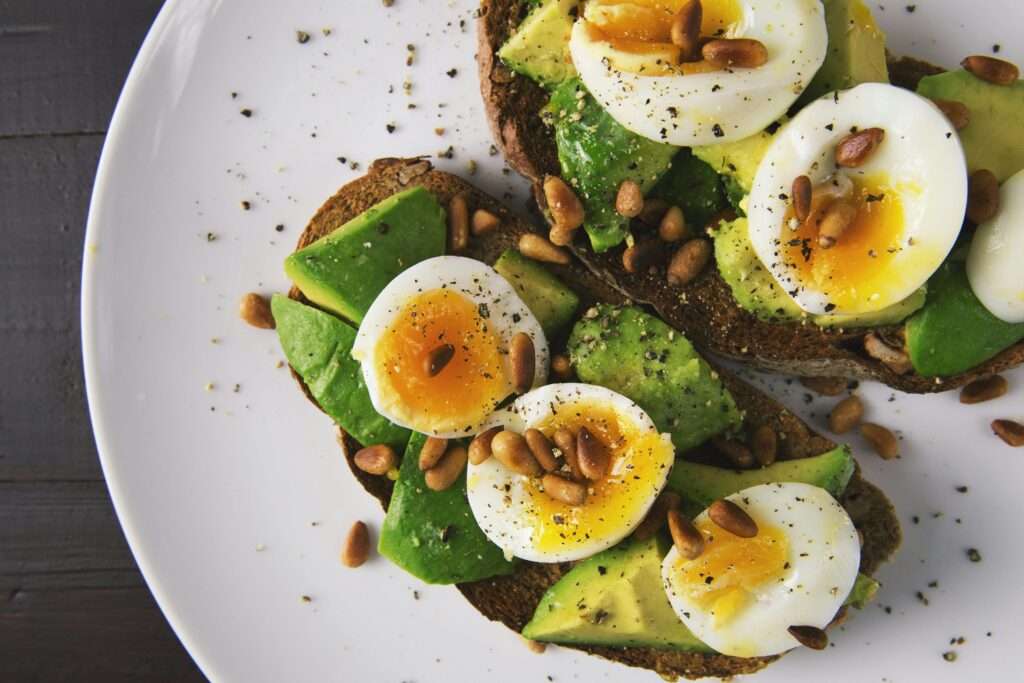 Ingredientes frescos y naturales para una alimentación saludable: huevos, aguacate, aceite de oliva, verduras y especias sobre una mesa rústica de madera.